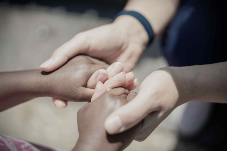 A supportive hand holding another in a comforting gesture, symbolizing emotional connection, compassion, and mental health support.