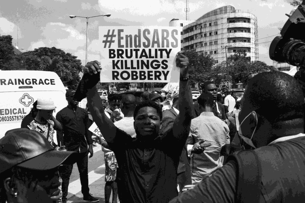 Young Nigerian man holding an EndSARS protest sign against police brutality Yelewata And Daudu