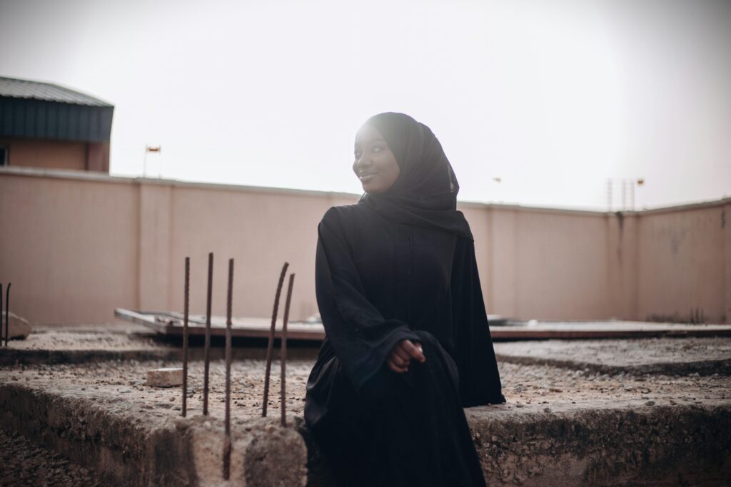 A young Muslim girl in black hijab sits alone in quiet reflection, symbolizing inner struggle and hope.
