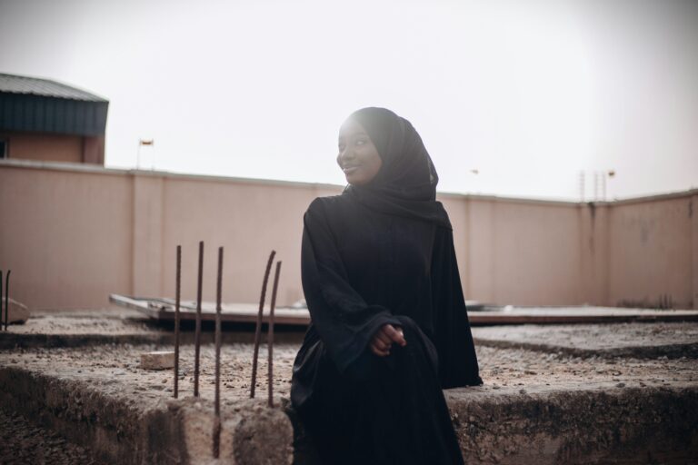 A young Muslim girl in black hijab sits alone in quiet reflection, symbolizing inner struggle and hope.