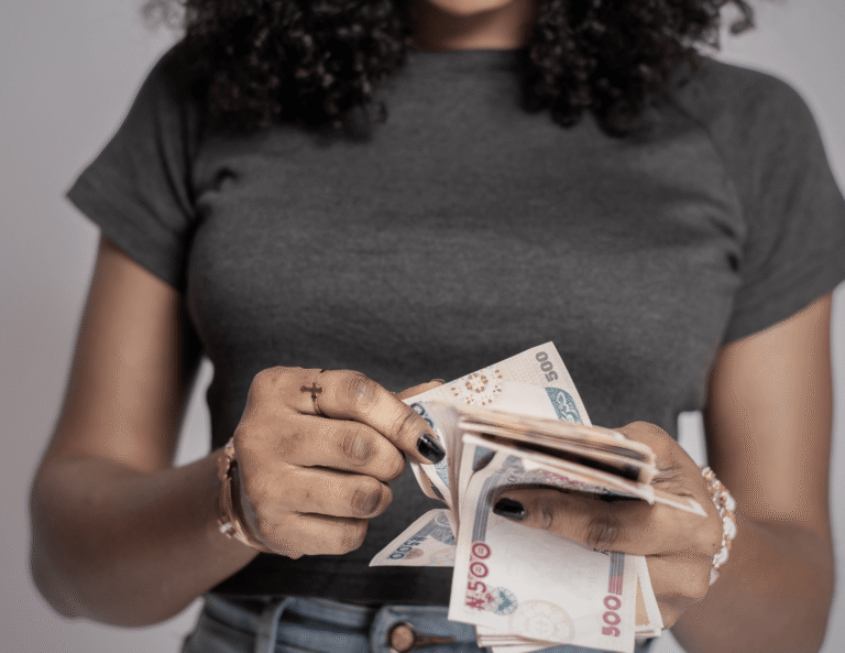 A woman holding and counting naira notes with her face out of frame, symbolizing financial struggles and the emotional weight of money stress.