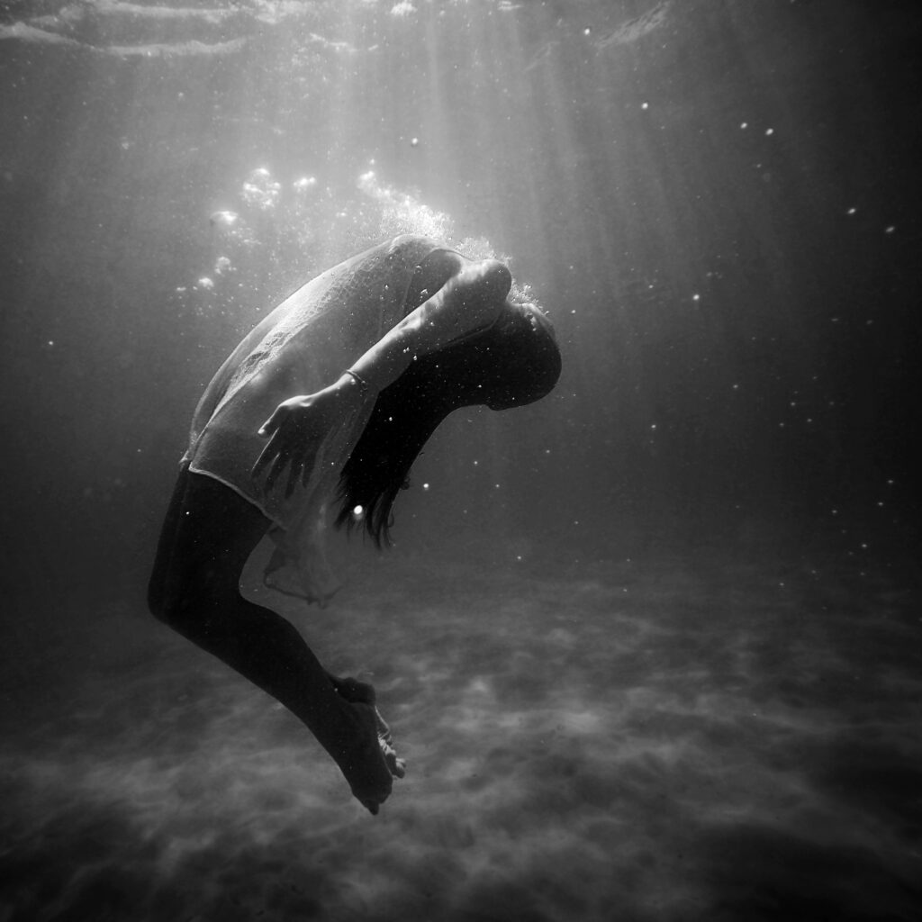 a woman slowly drowning deep under water, symbolizing depression emotional overwhelm