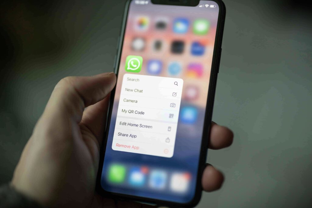 Person holding a smartphone, deleting an app from their device to declutter digital space.