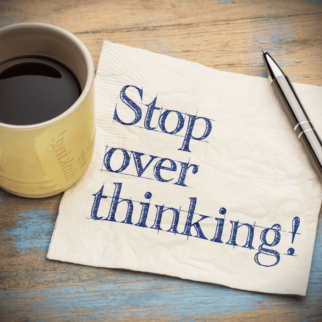 A cup of coffee beside a tissue paper with the words “Stop overthinking,” symbolising overthinking as an insidious habit driven by fear and anxiety.