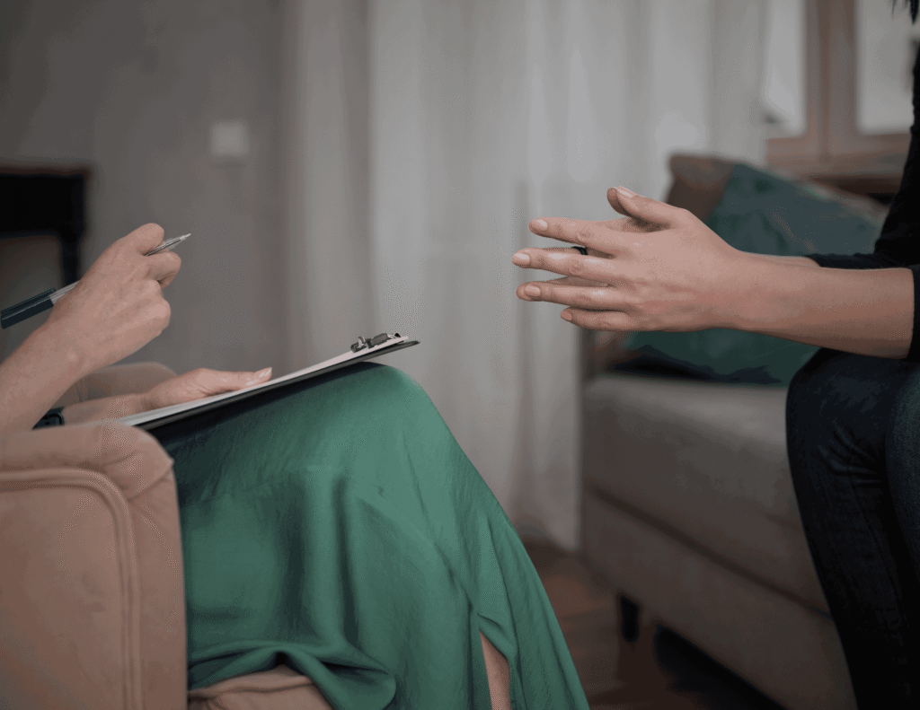 A client speaking to a mental health counsellor during a counselling session while the therapist takes notes on a clipboard