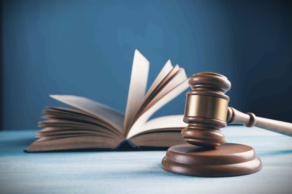 Wooden judge’s gavel resting in front of an open book on a desk.