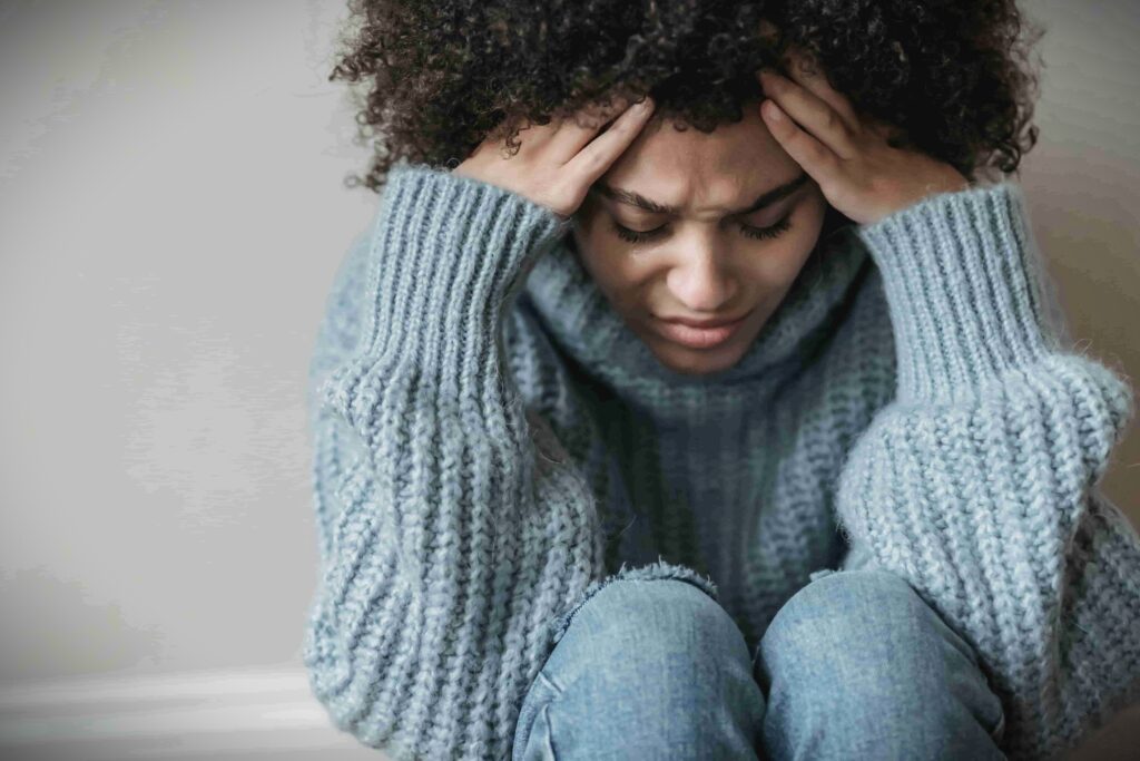 Woman sitting with her head in her hands, appearing mentally and emotionally exhausted, symbolizing burnout from content creation pressure.