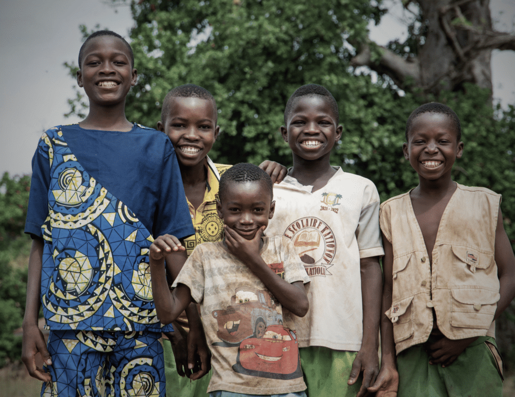Five African children smiling together outdoors, representing children growing up in a polygamous family in Nigeria