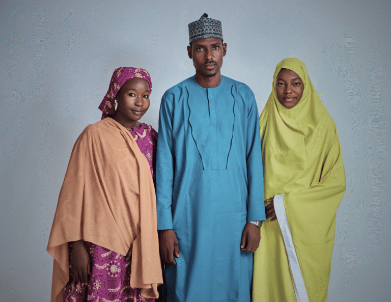 Nigerian man in traditional attire standing between two women in hijabs, representing a polygamous family structure in Nigeria