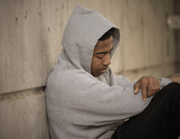 A depressed teenage boy sitting alone against a wall representing the silent struggle of teen suicide in Africa
